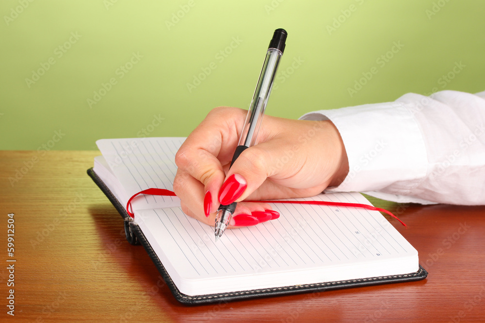 Hand signing in notebook  on wooden table on color background