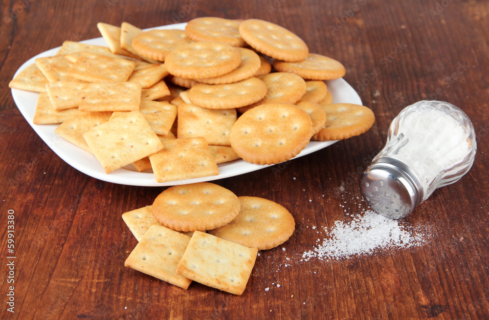 Delicious crackers with salt on wooden background