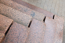 Old Stairs Made Of Red Granite On Gray Pavement