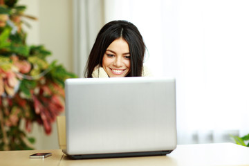 Poster - Young cheerful woman working on a laptop at home