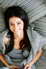 Poster - Cheerful woman lying on the floor with pillows. View from above