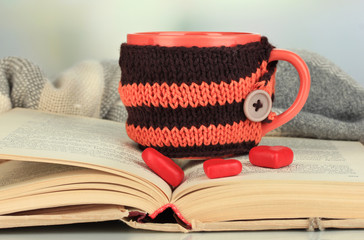 Fototapete - Cup with knitted thing on it and open book close up