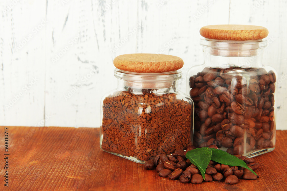 Jars of different coffee on table on wooden background