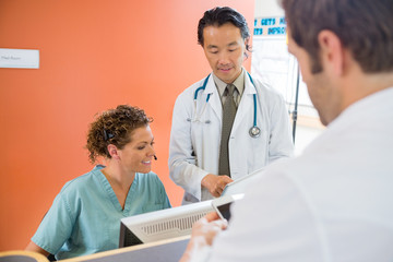 Wall Mural - Medical Team Using Digital Tablet While Patient Standing At Rece