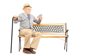 Poster - Senile old man with cane, on bench imagining playing cards with