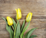 Fototapeta Tulipany - Beautiful yellow tulips on wooden background. Top view