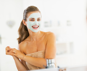 Wall Mural - Portrait of smiling young woman with cosmetic mask on face