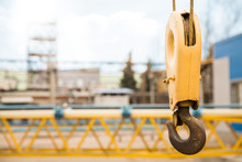 Yellow Construction Crane Hook With Some Industrial Buildings On The Background