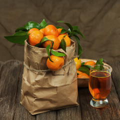 Wall Mural - Fresh tangerines in recycle paper bag and glass of juice on wood