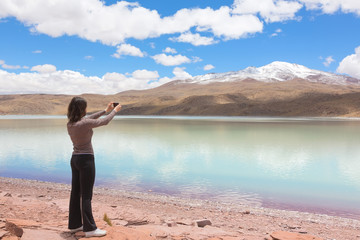 Woman taking pictures of lagoon Celeste, Bolivia