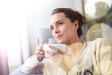 Peaceful woman relaxing at home with cup of tea