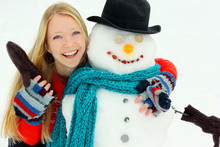 Happy Woman Hugging Snowman Outside In Winter
