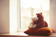 Two Embracing Teddy Bear Toys Sitting On Window-sill
