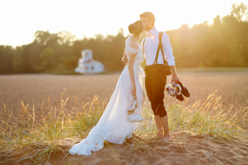 Wall Mural - Bride and groom on a beach at sunset