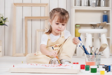 Little girl artist paints in his studio