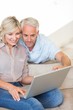 © WavebreakMediaMicro - Mature couple using laptop on sofa at home