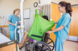 Nurses Transferring Patient From Hydraulic Lift To Wheelchair