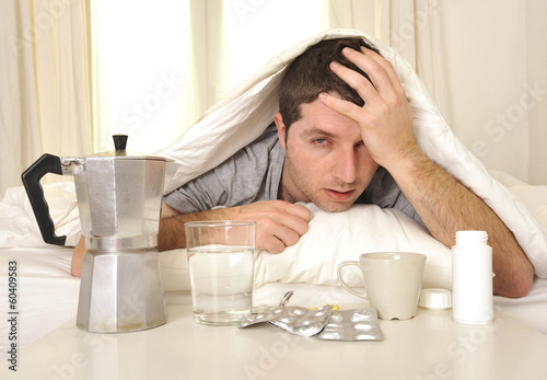 Fotografie, Obraz Man with headache and hangover in bed with tablets