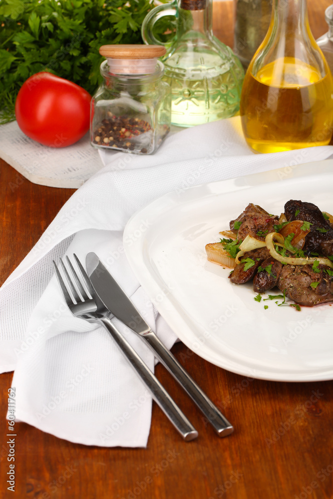 Fried chicken livers on plate on wooden table close-up