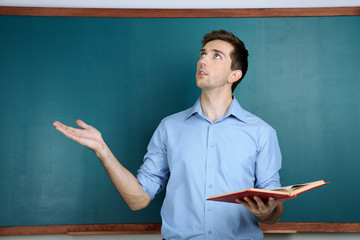 Canvas Print - Young teacher near chalkboard in school classroom