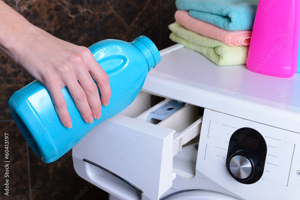 Female hands poured powder in washing machine close-up