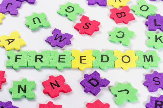 word FREEDOM formed with colorful foam puzzle  on white backgrou
