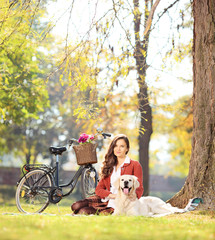 Beautiful female sitting on a grass with her dog in a park