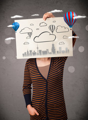 Wall Mural - Woman holding a cardboard with cityscape in front of her head