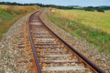 Rusty Railroad Tracks On A Railway Embankment Between Meadows