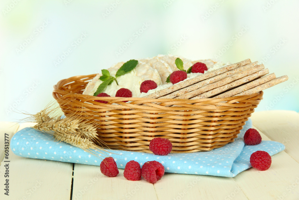 Tasty crispbread with berries in wicker basket, on white table