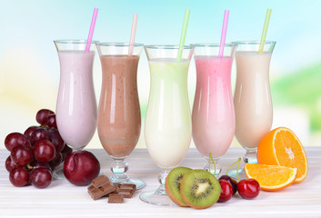 Wall Mural - Milk shakes with fruits on table on light blue background