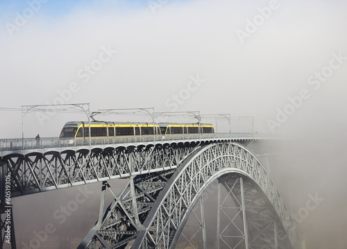 Fototapeta na wymiar Metro Train on the Bridge Built by Eiffel in Porto, foggy mornin