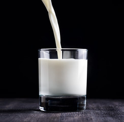 Canvas Print - Milk pouring into a glass on black board