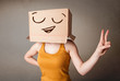 Young woman gesturing with a cardboard box on her head with smil