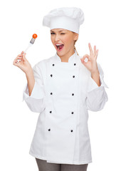 Poster - smiling female chef with fork and tomato