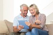 © WavebreakmediaMicro - Smiling mature couple using digital tablet on sofa
