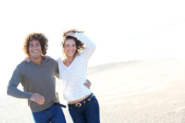 Wall Mural - Cheerful couple running on the beach