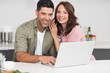 © WavebreakMediaMicro - Portrait of a happy couple using laptop in kitchen