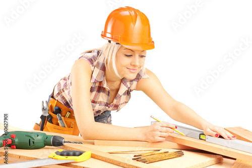 Fototapeta na wymiar Blond female carpenter measuring a batten