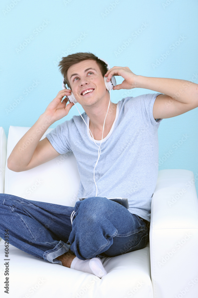 Guy sitting on sofa and  listening to music on blue background