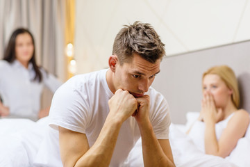 Canvas Print - man sitting on the bed with two women on the back