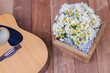 Acoustic Guitar on Wooden background and white flowers
