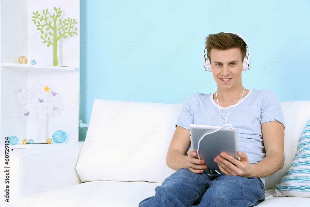 Guy sitting on sofa and  listening to music on blue background