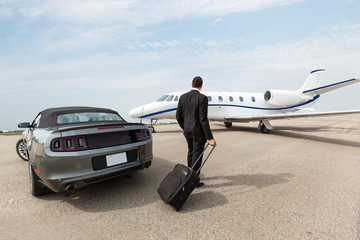 Wall Mural - Businessman Standing By Car And Private Jet At Terminal