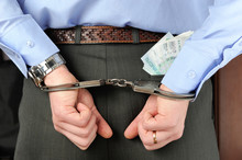 Man's Hands In Handcuffs With Money In His Pocket