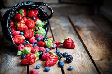 Wall Mural - Mix of fresh berries in a basket on rustic wooden background