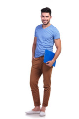 Wall Mural - full body picture of a young casual man holding  notepad