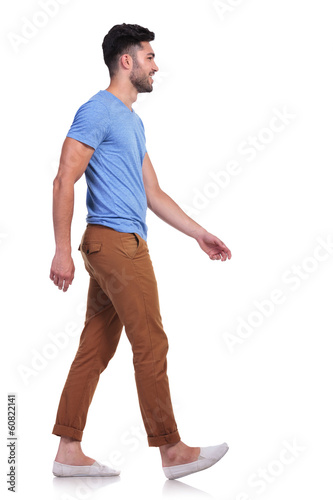 Fotografía side view of a casual man walking forward and smiling