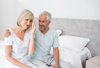 Wall Mural - Smiling man and woman sitting on bed