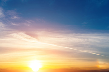 Dramatic sunset sky with orange colored clouds and sun.